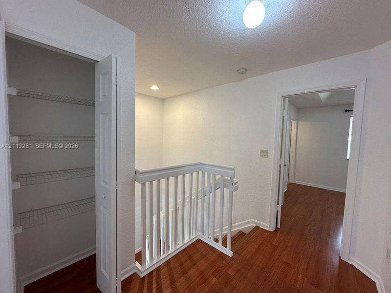 2615 SE 15th Place, #190, Homestead, FL 33035 Hallway featuring wood-finish flooring, white picket-style stair railing, and a built-in closet with wire shelving