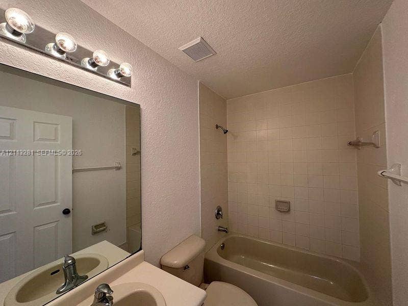 2615 SE 15th Place, #190, Homestead, FL 33035 Bathroom featuring a vanity with integrated sink, large wall-mounted mirror, four-light vanity fixture, and a tiled tub-shower combination