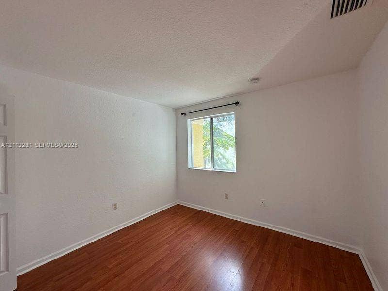 2615 SE 15th Place, #190, Homestead, FL 33035 Interior space featuring wood-finish flooring, white walls, and a window with a mounted curtain rod