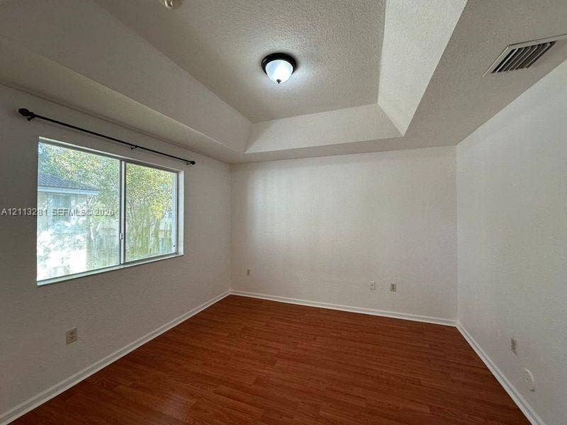 2615 SE 15th Place, #190, Homestead, FL 33035 Tray ceiling, wood-finish flooring, and single-pane window with horizontal rod