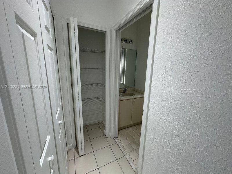 2615 SE 15th Place, #190, Homestead, FL 33035 Storage area featuring floor-to-ceiling bi-fold doors, white wire shelving, tiled flooring, and a vanity with a neutral-toned countertop