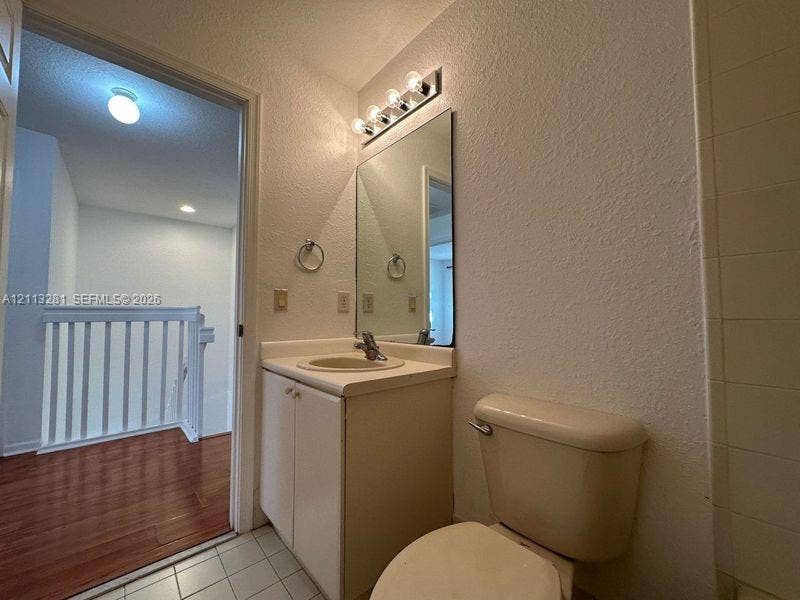 2615 SE 15th Place, #190, Homestead, FL 33035 Bathroom featuring a vanity with an integrated sink, wall-mounted four-bulb lighting fixture, rectangular mirror, and tile flooring