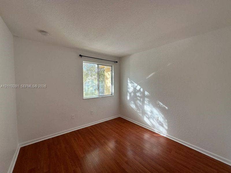 2615 SE 15th Place, #190, Homestead, FL 33035 Room featuring wood-finish flooring, textured walls, and a single-pane sliding window with an integrated curtain rod