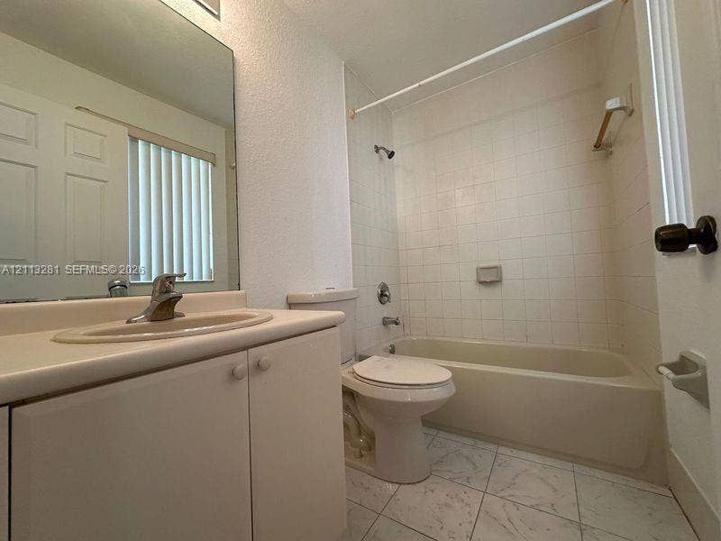 2615 SE 15th Place, #190, Homestead, FL 33035 Bathroom featuring a vanity with an integrated sink, large wall-mounted mirror, ceramic tile flooring, and a tiled tub-shower combination