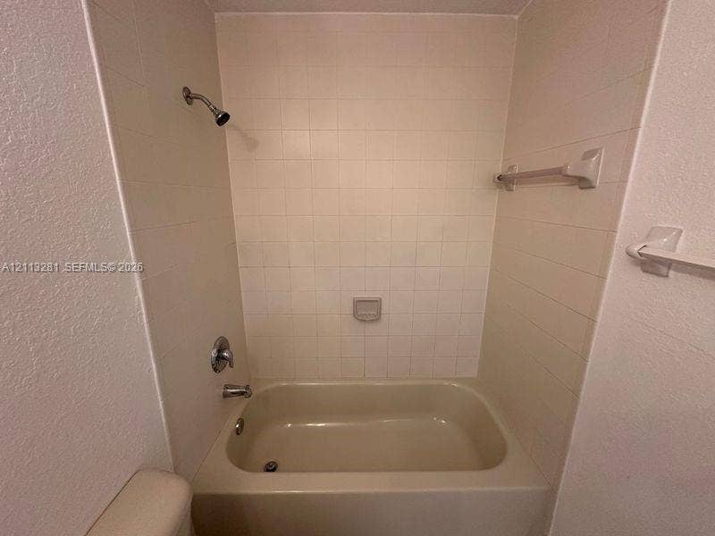 2615 SE 15th Place, #190, Homestead, FL 33035 Bathtub surround featuring square ceramic tile, built-in soap dish, chrome shower head, and wall-mounted towel bars