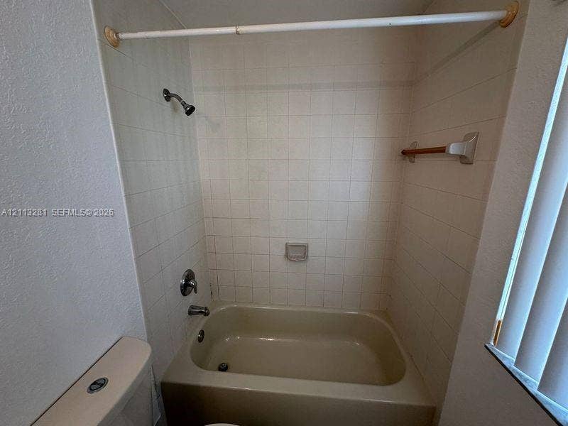 2615 SE 15th Place, #190, Homestead, FL 33035 Full-height square wall tile surround, built-in soap dish, porcelain bathtub, chrome shower fixture, and wall-mounted towel bar