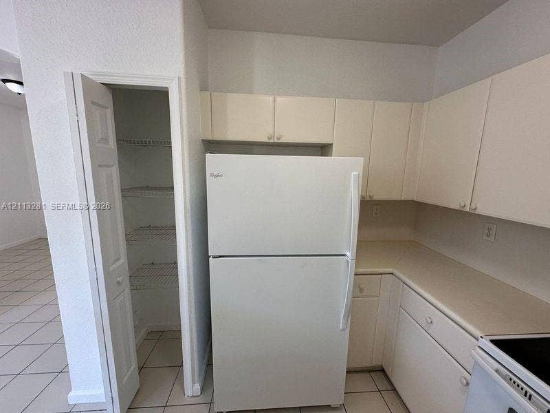 2615 SE 15th Place, #190, Homestead, FL 33035 Kitchen area featuring white cabinetry, solid surface countertops, and an integrated pantry with wire shelving
