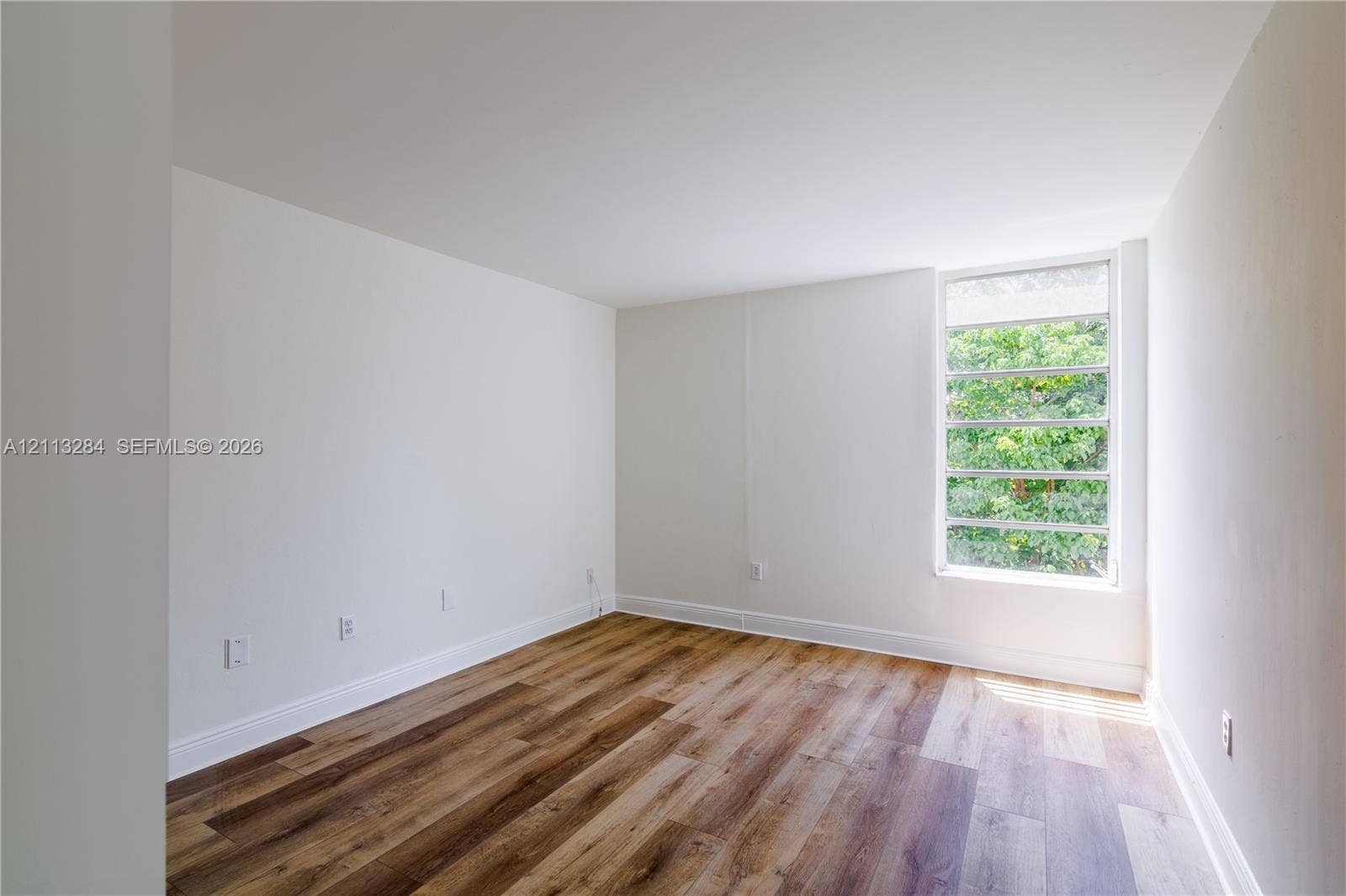 Neutral-toned room with wood-finish flooring and a multi-pane horizontal window