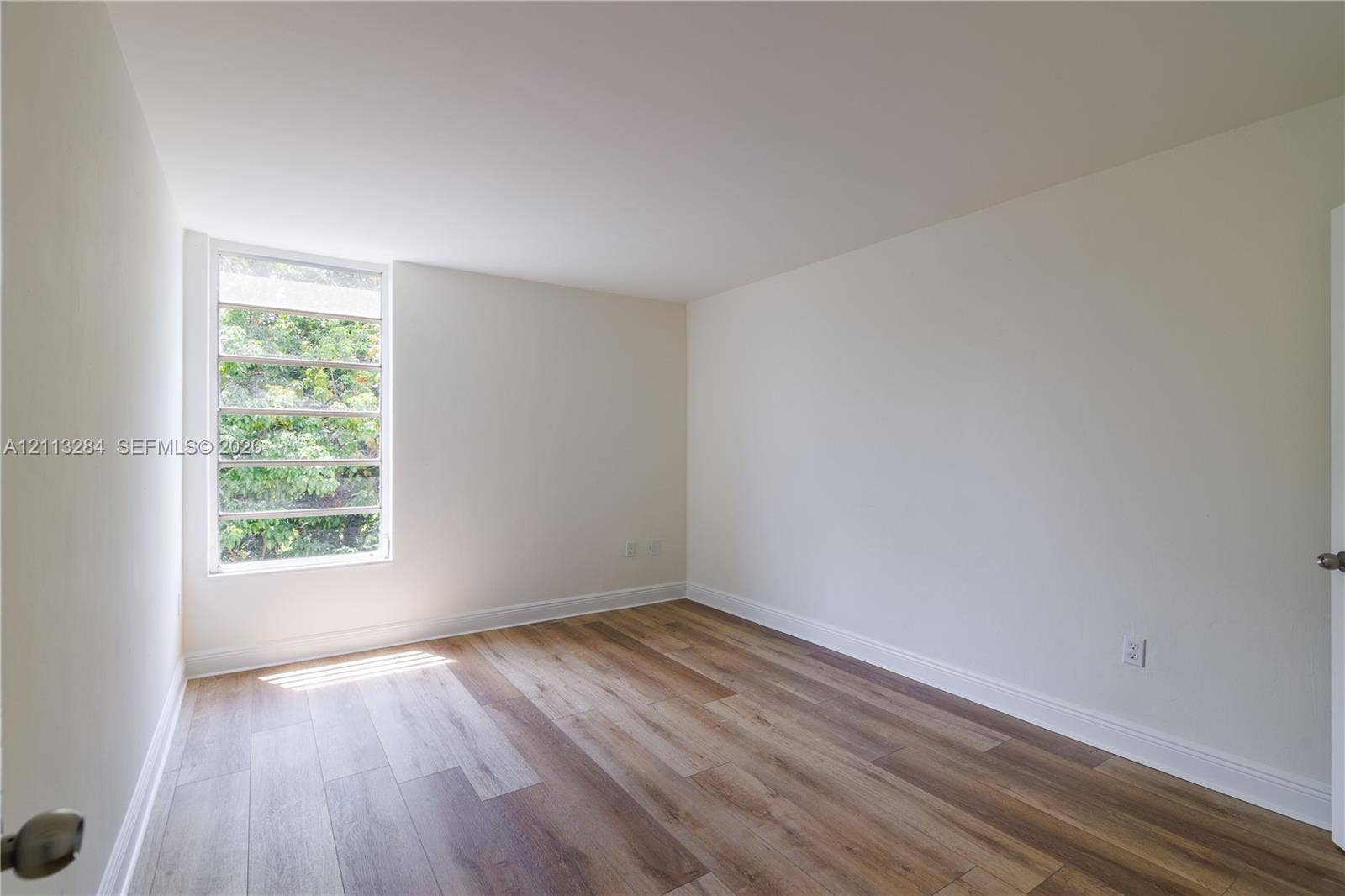 Neutral interior room featuring wood-finish flooring and a multi-pane horizontal window