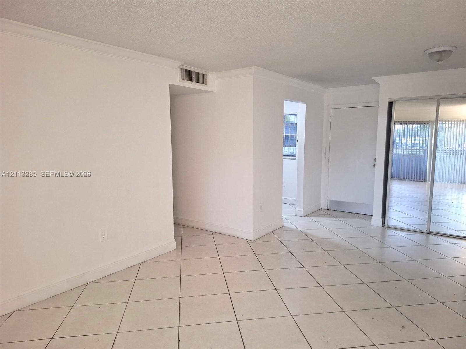 Neutral-toned ceramic tile flooring, mirrored sliding closet doors, flush-mount ceiling lighting, and crown molding