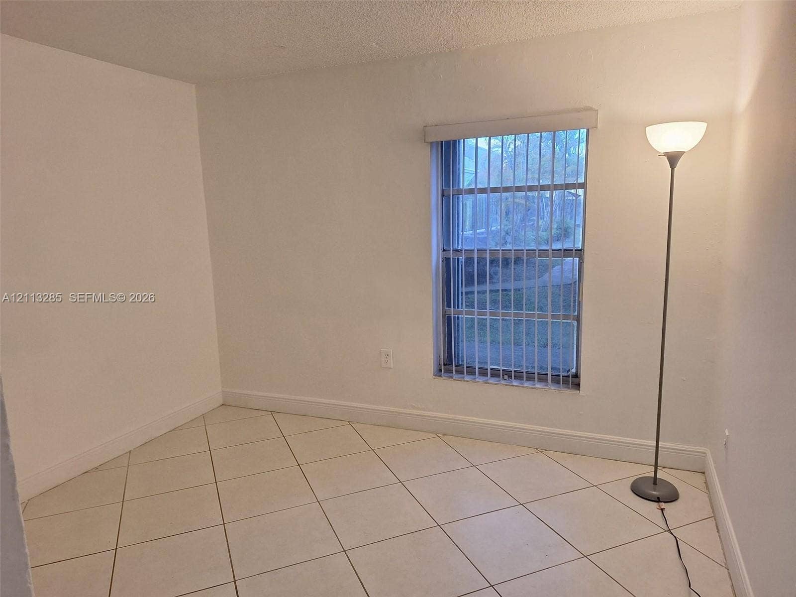Neutral-toned ceramic tile flooring, vertical window blinds, and crisp white wall finishes