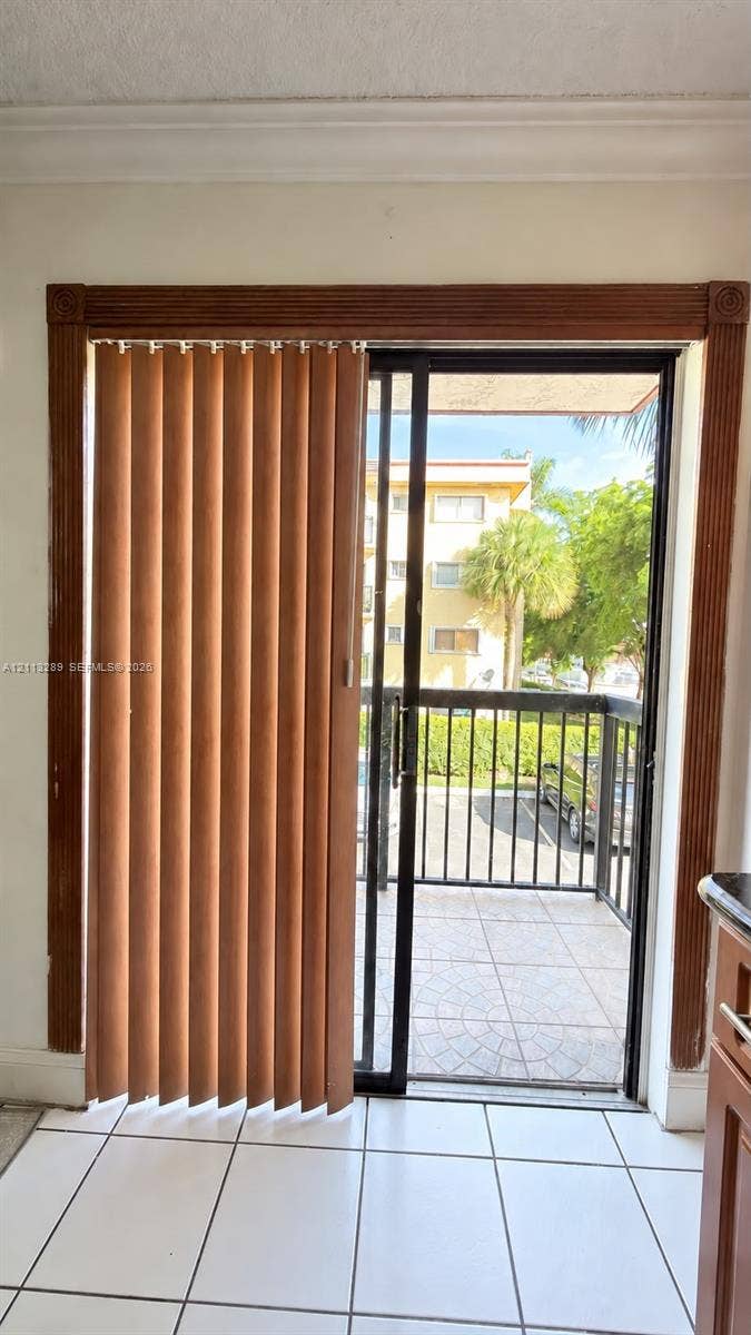 5460 W 21st Court, #208, Hialeah, FL 33016 Sliding glass door featuring a black metal frame, ornate wooden molding surround, and ceramic tile flooring