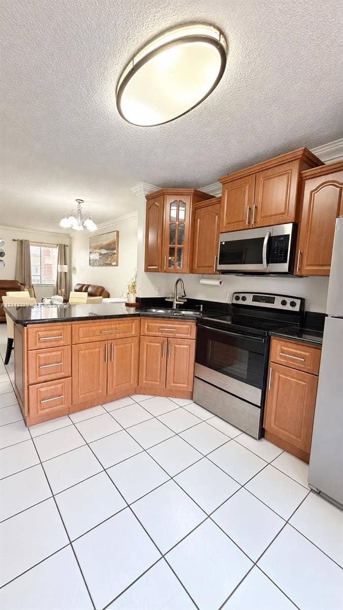 5460 W 21st Court, #208, Hialeah, FL 33016 Kitchen featuring wood cabinetry, stone countertops, stainless steel appliances, ceramic tile flooring, and a flush-mount overhead light fixture