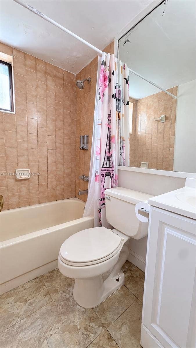 5460 W 21st Court, #208, Hialeah, FL 33016 Full-height wall tiling, integrated bathtub, large wall-mounted mirror, white vanity cabinetry, and tile flooring