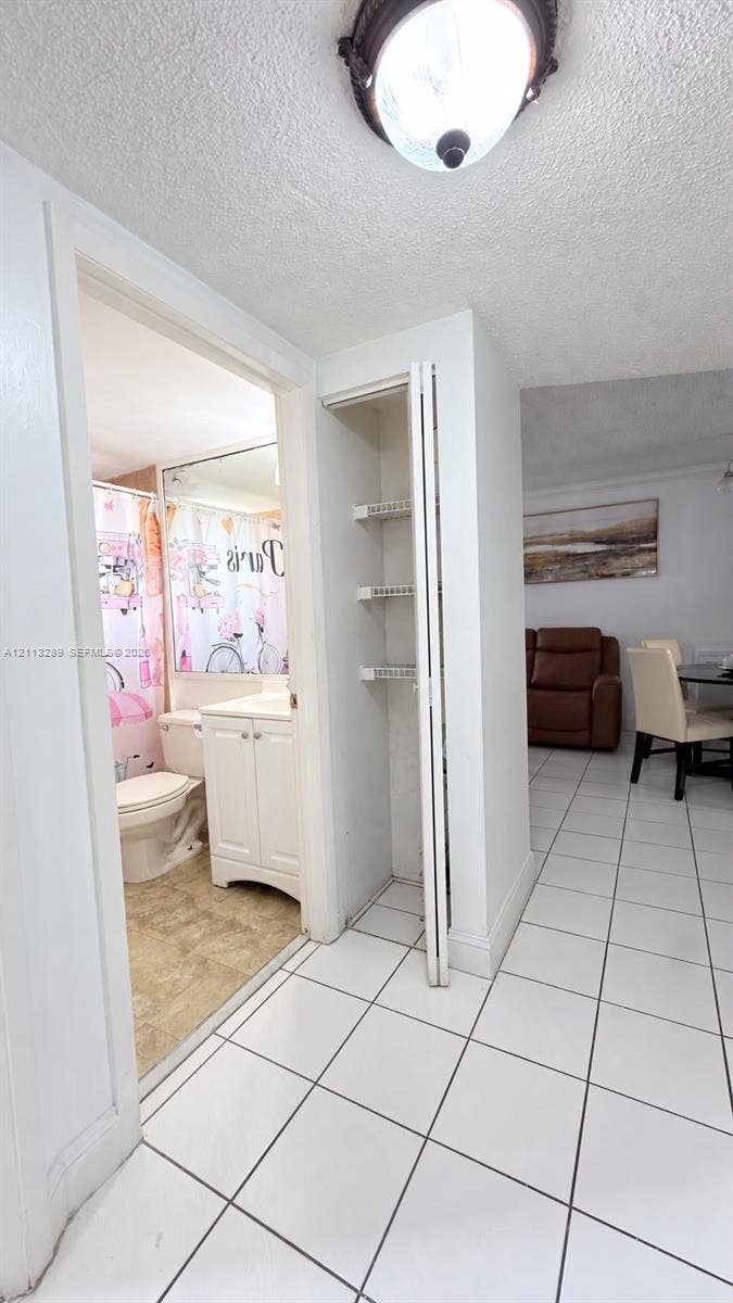 5460 W 21st Court, #208, Hialeah, FL 33016 Ceramic tile flooring, built-in recessed shelving, wall-mounted flush-mount lighting, and white cabinetry