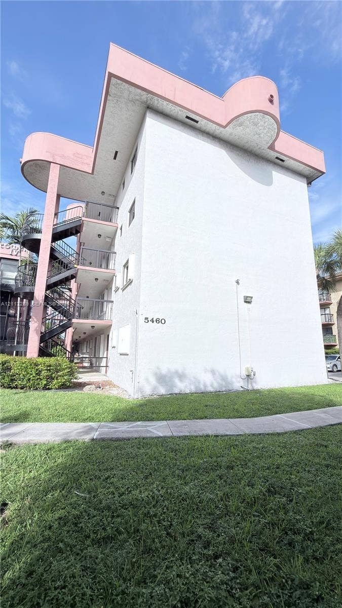 5460 W 21st Court, #208, Hialeah, FL 33016 Mid-rise building featuring a stucco exterior, curvilinear architectural accents, multi-level exterior staircases, and concrete walkways