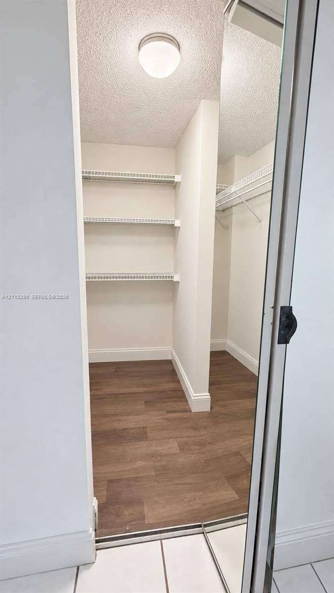 5460 W 21st Court, #208, Hialeah, FL 33016 Walk-in closet featuring wood-finish flooring, white built-in wire shelving, and a mirrored sliding door