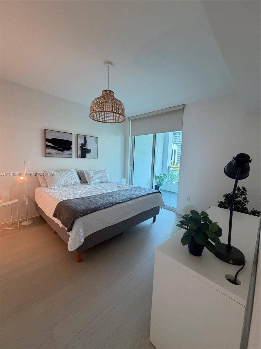 951 Brickell Avenue, #405, Miami, Miami, FL 33131 Light-toned wood-finish flooring, textured woven pendant lighting, floor-to-ceiling glass sliding doors, and access to a private balcony