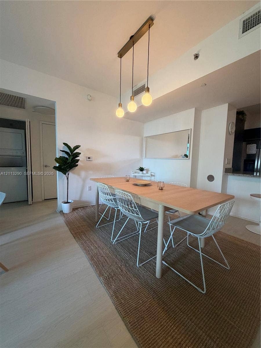 951 Brickell Avenue, #405, Miami, Miami, FL 33131 Multi-pendant linear light fixture with exposed bulbs, neutral wood-finish flooring, and wall-mounted mirror
