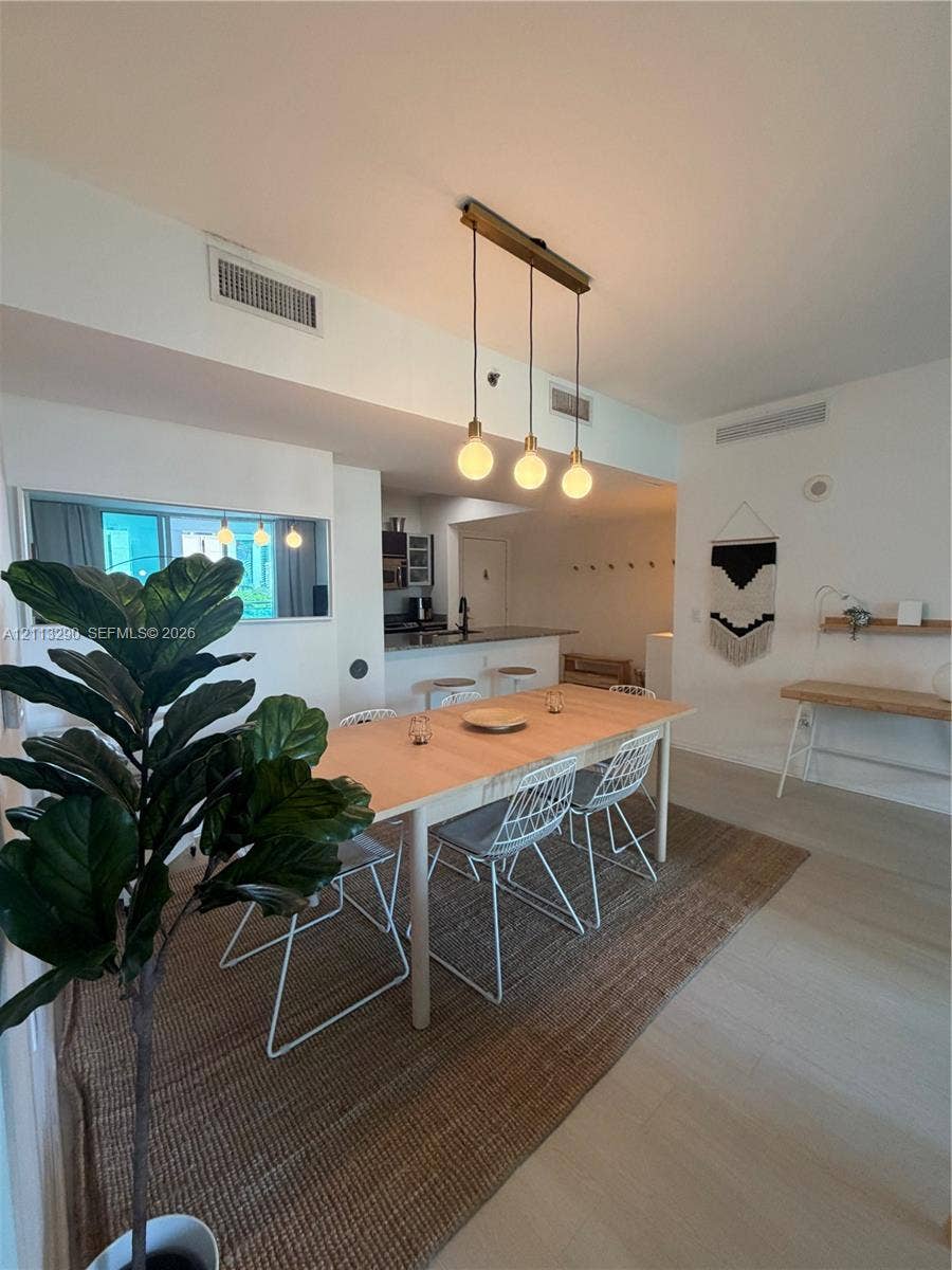 951 Brickell Avenue, #405, Miami, Miami, FL 33131 Open-concept interior featuring light-toned wood-finish flooring, a linear three-pendant light fixture, and a built-in wall shelf