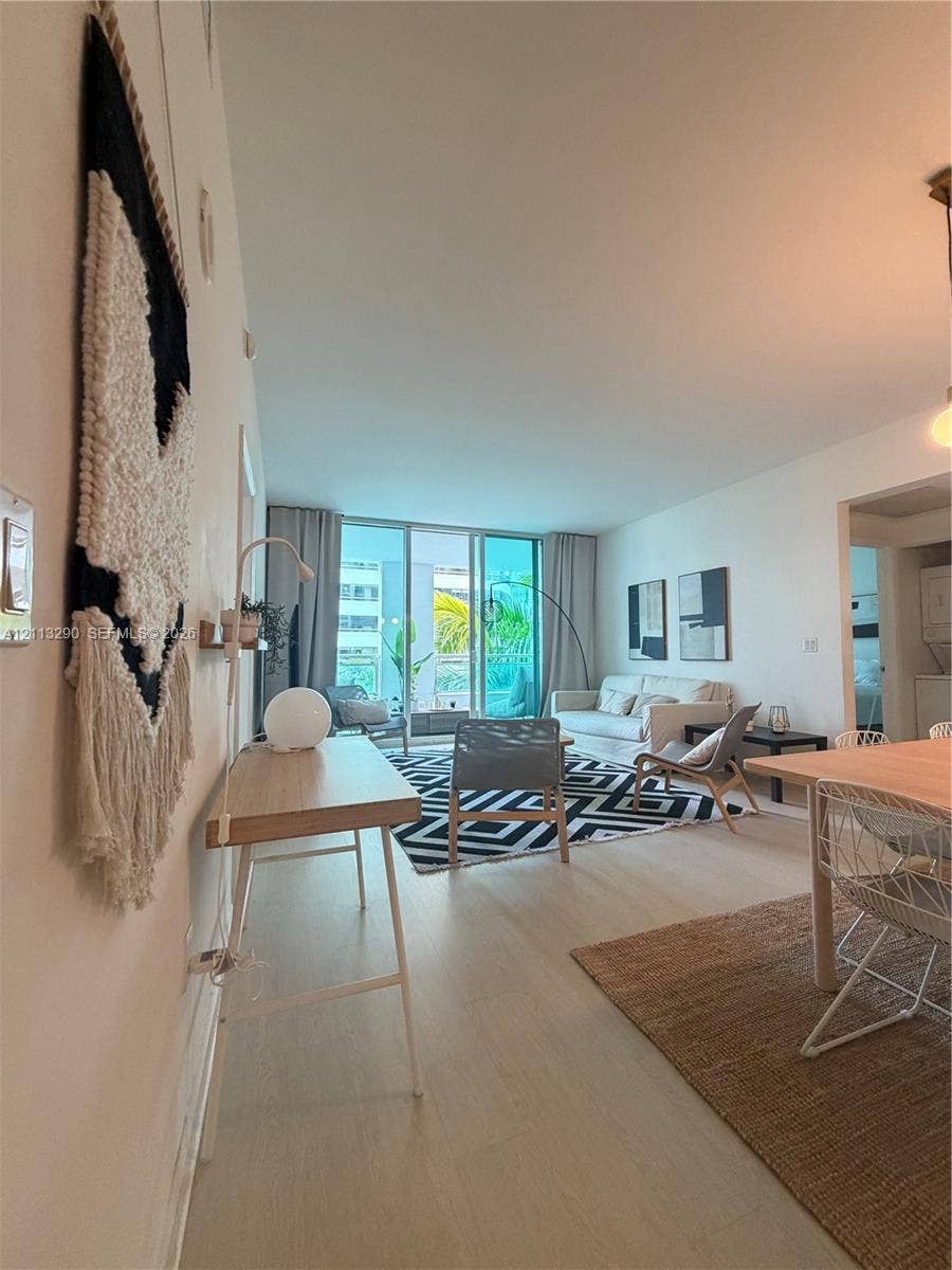 951 Brickell Avenue, #405, Miami, Miami, FL 33131 Open-concept interior featuring wood-finish flooring, high ceilings, and floor-to-ceiling glass doors providing access to a balcony