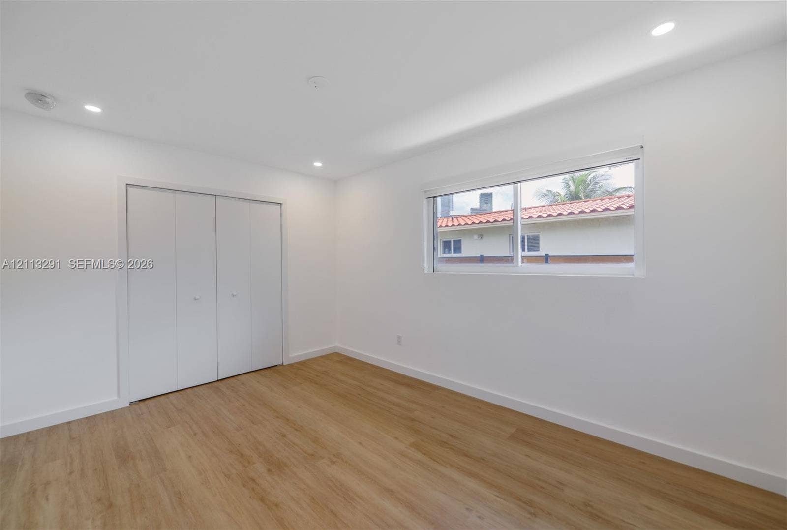 Neutral interior featuring wood-finish flooring, recessed lighting, and a double-door closet