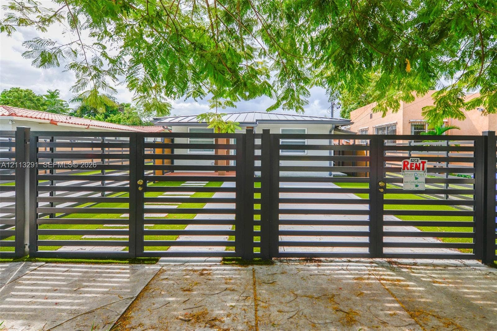 Horizontal slat metal entry gate with concrete paver walkway and synthetic turf lawn