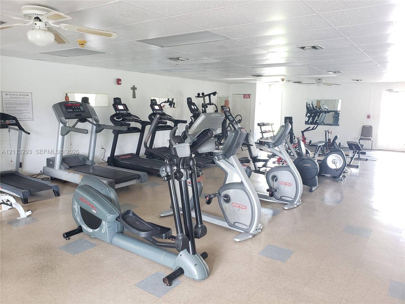 Fitness room featuring vinyl tile flooring, recessed ceiling lighting, and overhead paddle fans