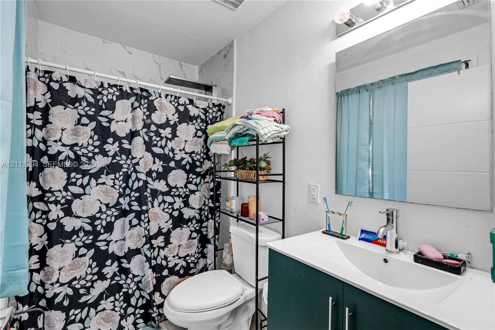 25880 SW 139th Path, #0, Homestead, FL 33032 Bathroom featuring a vanity with an integrated basin, chrome faucet, wall-mounted mirror, and a shower area with tiled wall surround