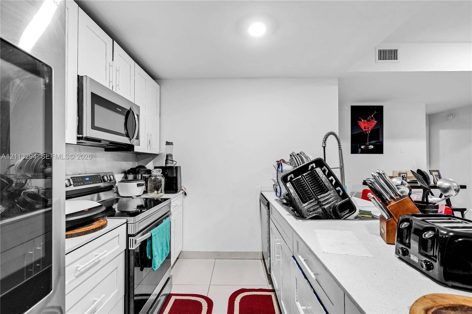 25880 SW 139th Path, #0, Homestead, FL 33032 Kitchen featuring white shaker-style cabinetry, stainless steel appliances, a high-arc pull-down faucet, and light-toned countertop surfaces