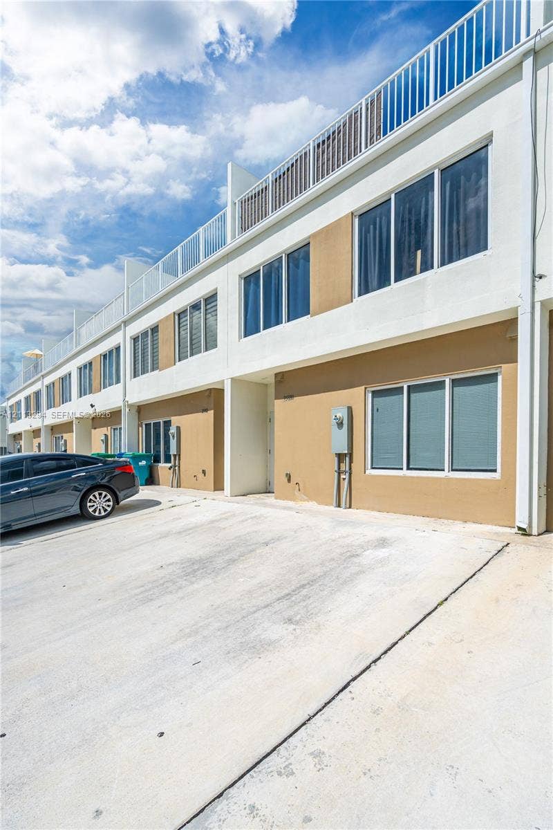 25880 SW 139th Path, #0, Homestead, FL 33032 Contemporary multi-story exterior featuring a concrete driveway, smooth stucco finish, oversized windows, and a railed rooftop terrace