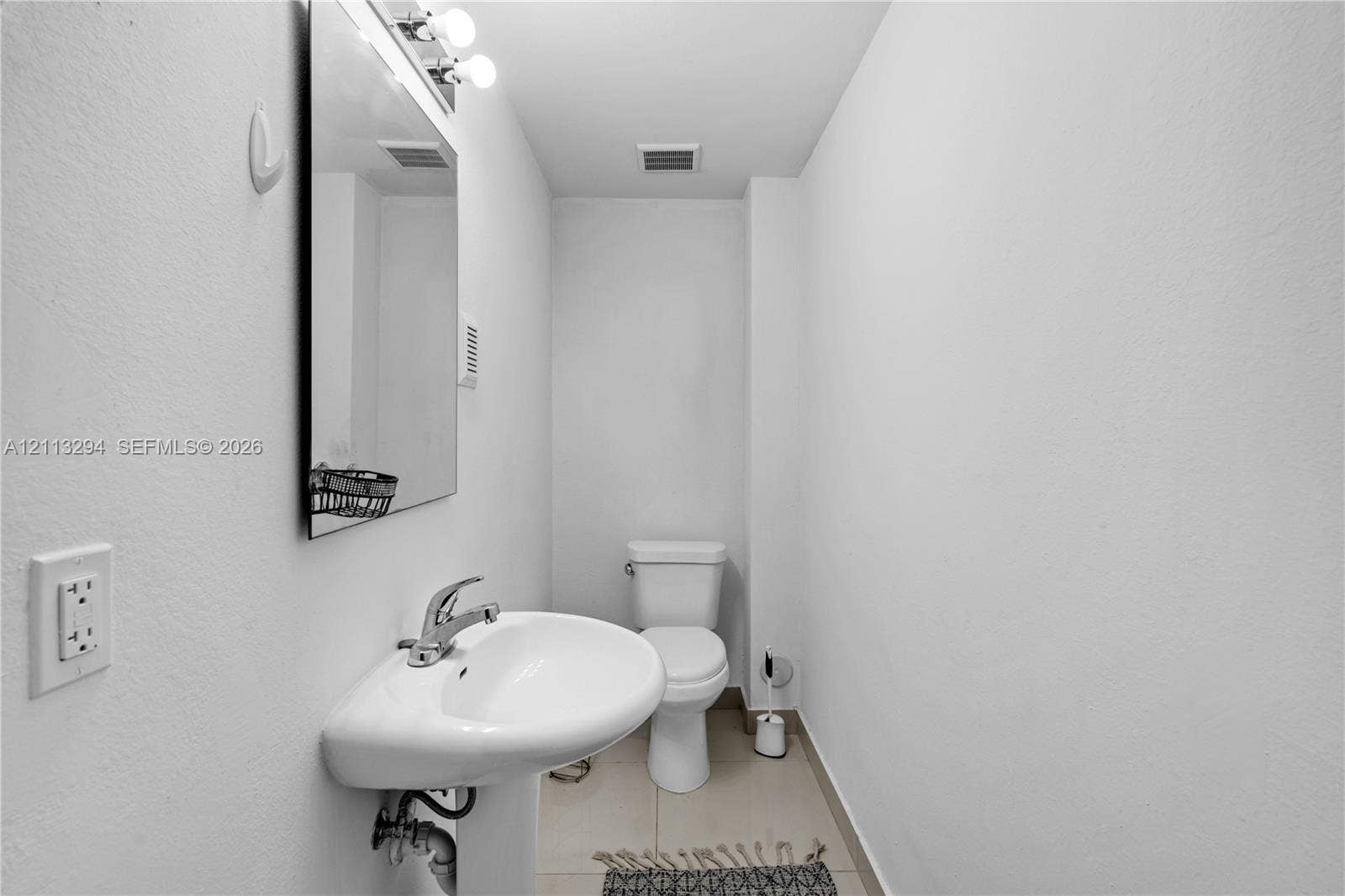 25880 SW 139th Path, #0, Homestead, FL 33032 Wall-mounted mirror with integrated lighting, pedestal sink with metal faucet, and floor-mounted toilet
