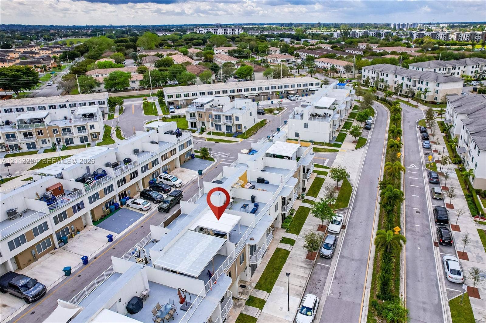 25880 SW 139th Path, #0, Homestead, FL 33032 Aerial perspective of multi-level townhome featuring a rooftop terrace, metal railings, and paved surface parking