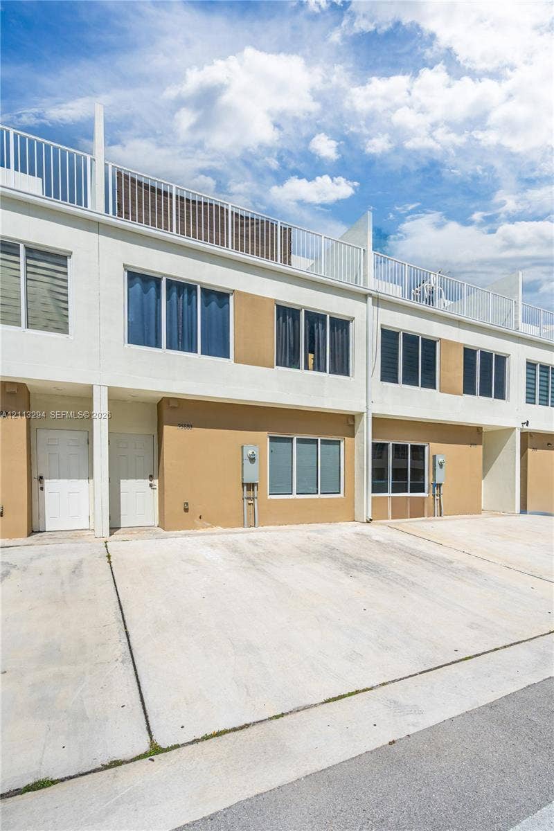 25880 SW 139th Path, #0, Homestead, FL 33032 Contemporary multi-level exterior featuring white and tan stucco cladding, horizontal window groupings, a flat roofline, and a private rooftop terrace with metal railings