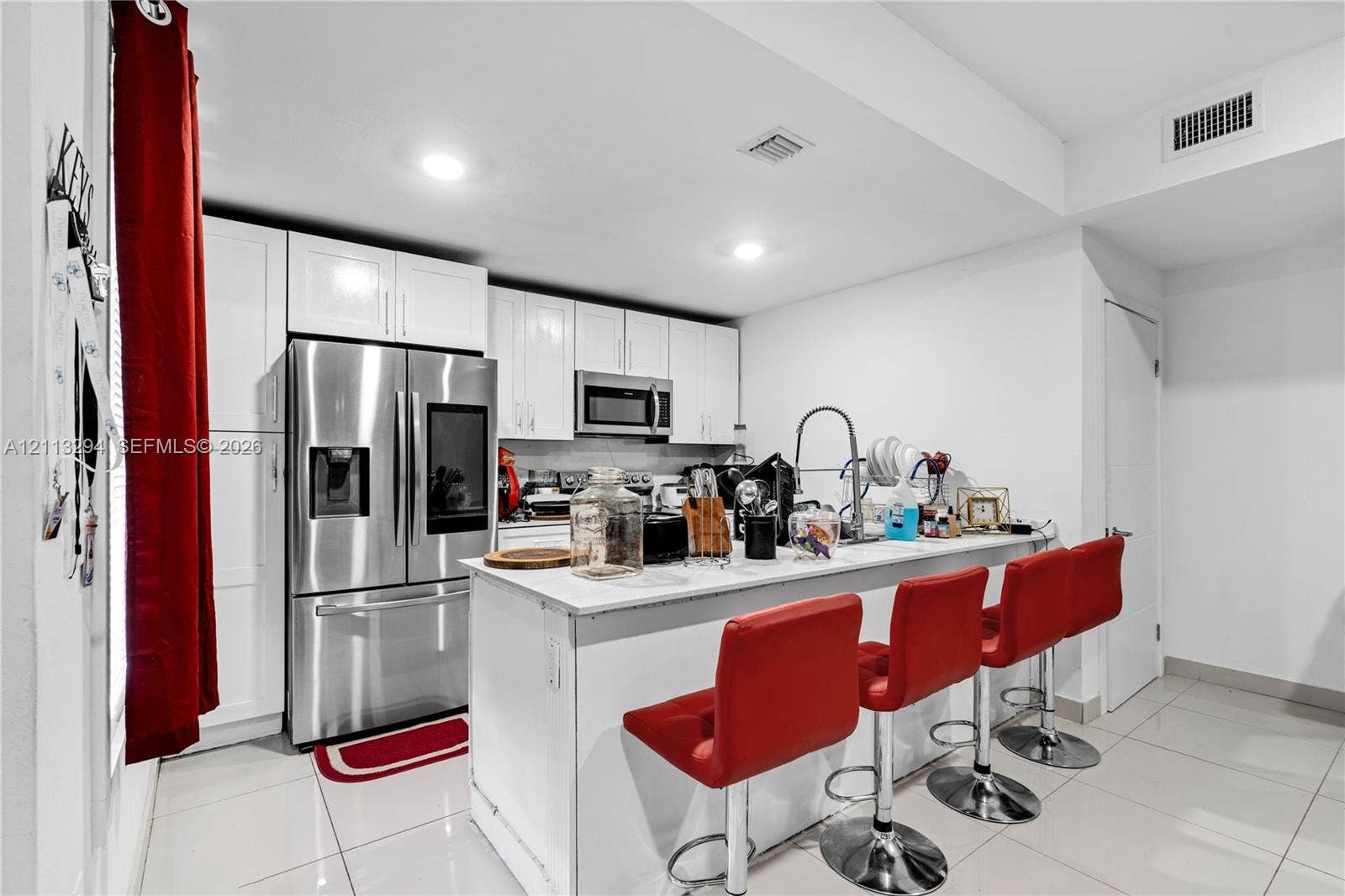 25880 SW 139th Path, #0, Homestead, FL 33032 Kitchen featuring white shaker-style cabinetry, stainless steel appliances, a breakfast bar with stone-finish countertops, and large-format tile flooring