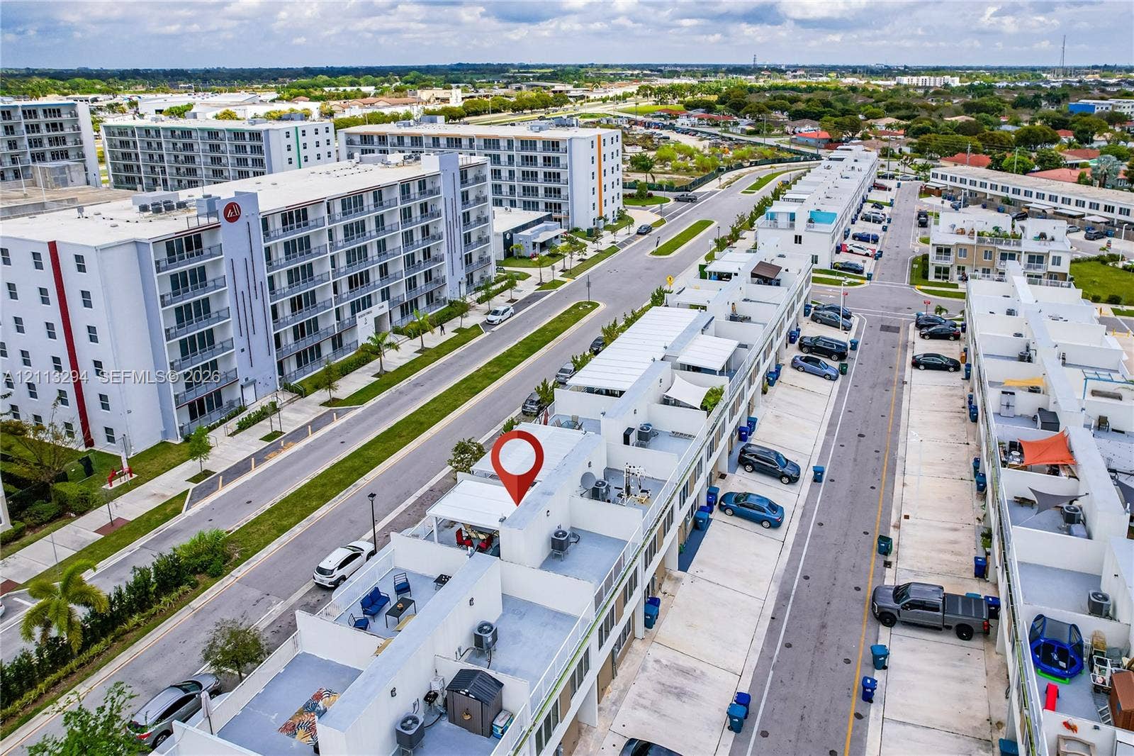 25880 SW 139th Path, #0, Homestead, FL 33032 Aerial perspective of a multi-level townhome featuring a rooftop terrace, concrete construction, paved parking surface, and individual exterior utility units
