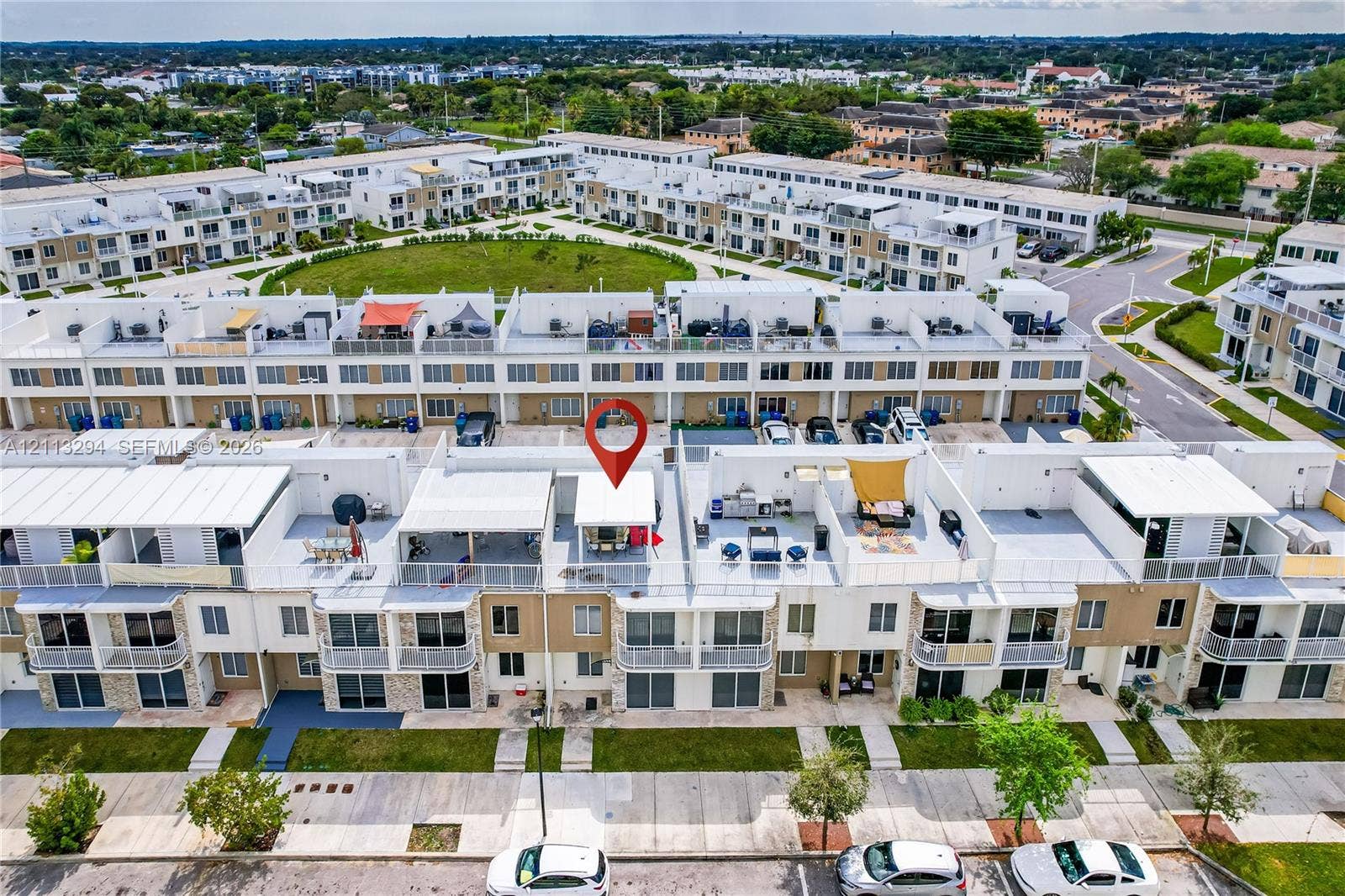 25880 SW 139th Path, #0, Homestead, FL 33032 Aerial perspective of a multi-level residential complex featuring tiered roof terraces, white metal railings, stone veneer accents, and paved parking areas