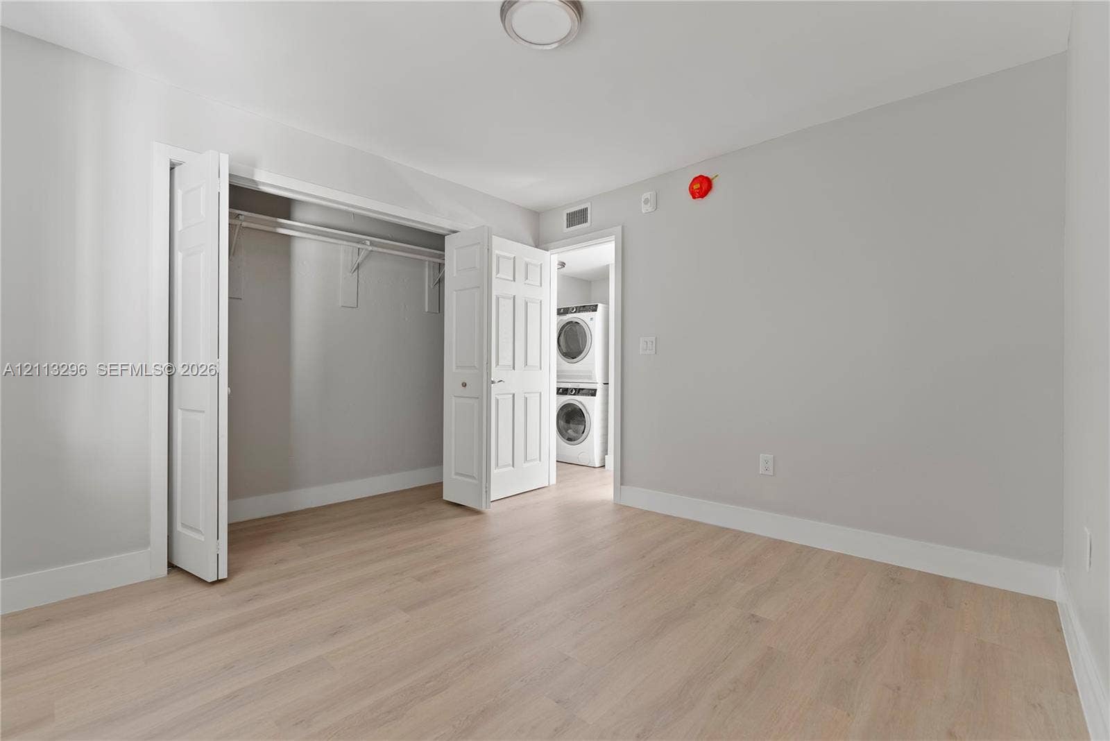 1101 NE 80th Street, #302, Miami, Miami, FL 33138 Wood-finish flooring, neutral wall tones, bi-fold closet doors, and a stacked washer and dryer unit
