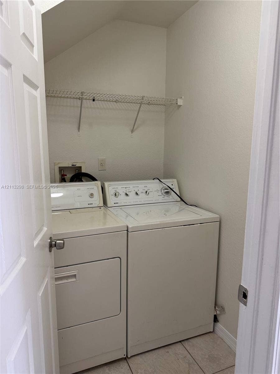 Dedicated laundry area featuring tile flooring and integrated wire shelving