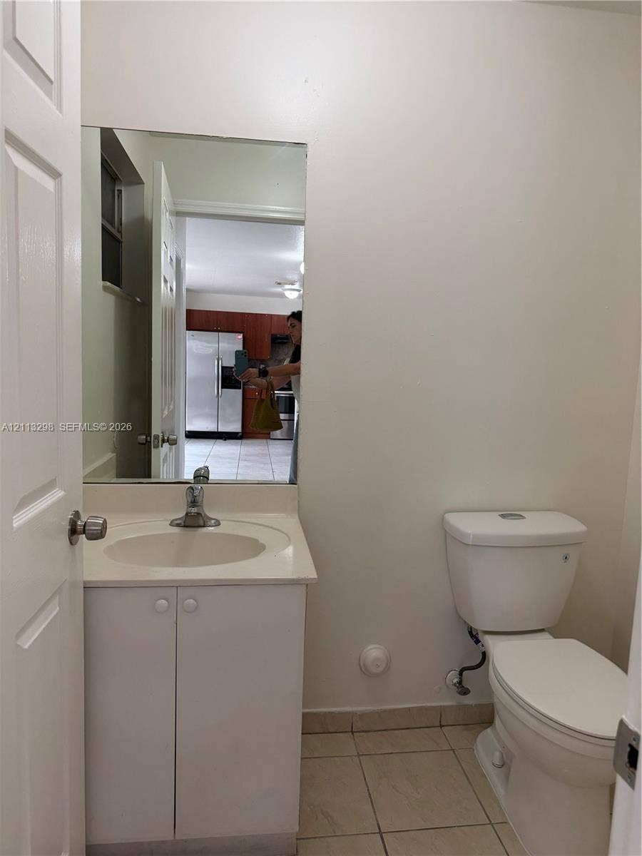 Wall-mounted vanity featuring a solid-surface integrated countertop, porcelain basin, single-handle faucet, and ceramic tile flooring