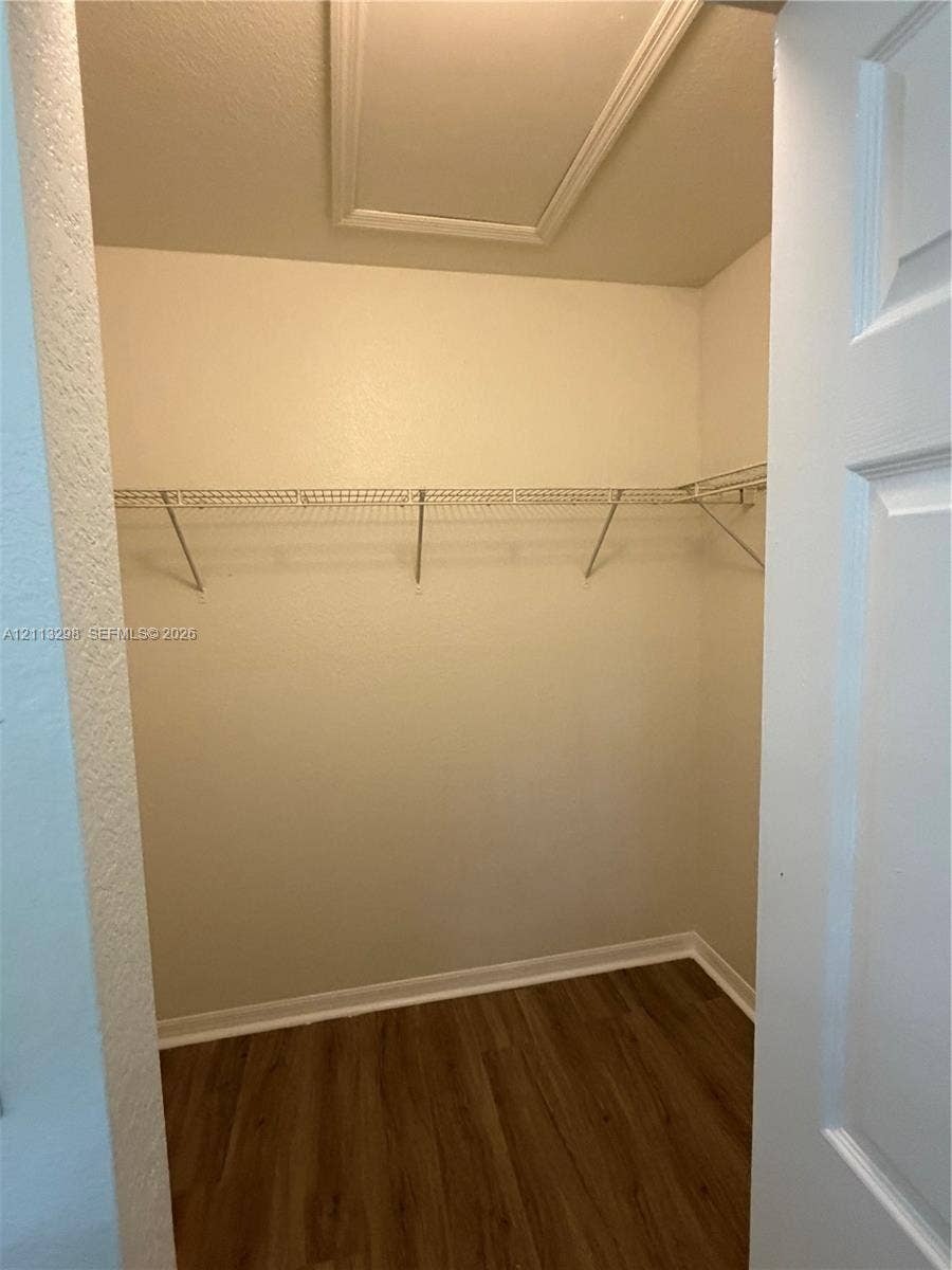 Storage area featuring wood-finish flooring, white walls, and wire shelving