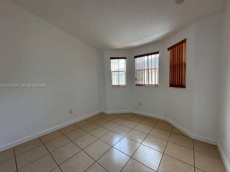 Room featuring tile flooring, a bay window configuration, and vertical window blinds
