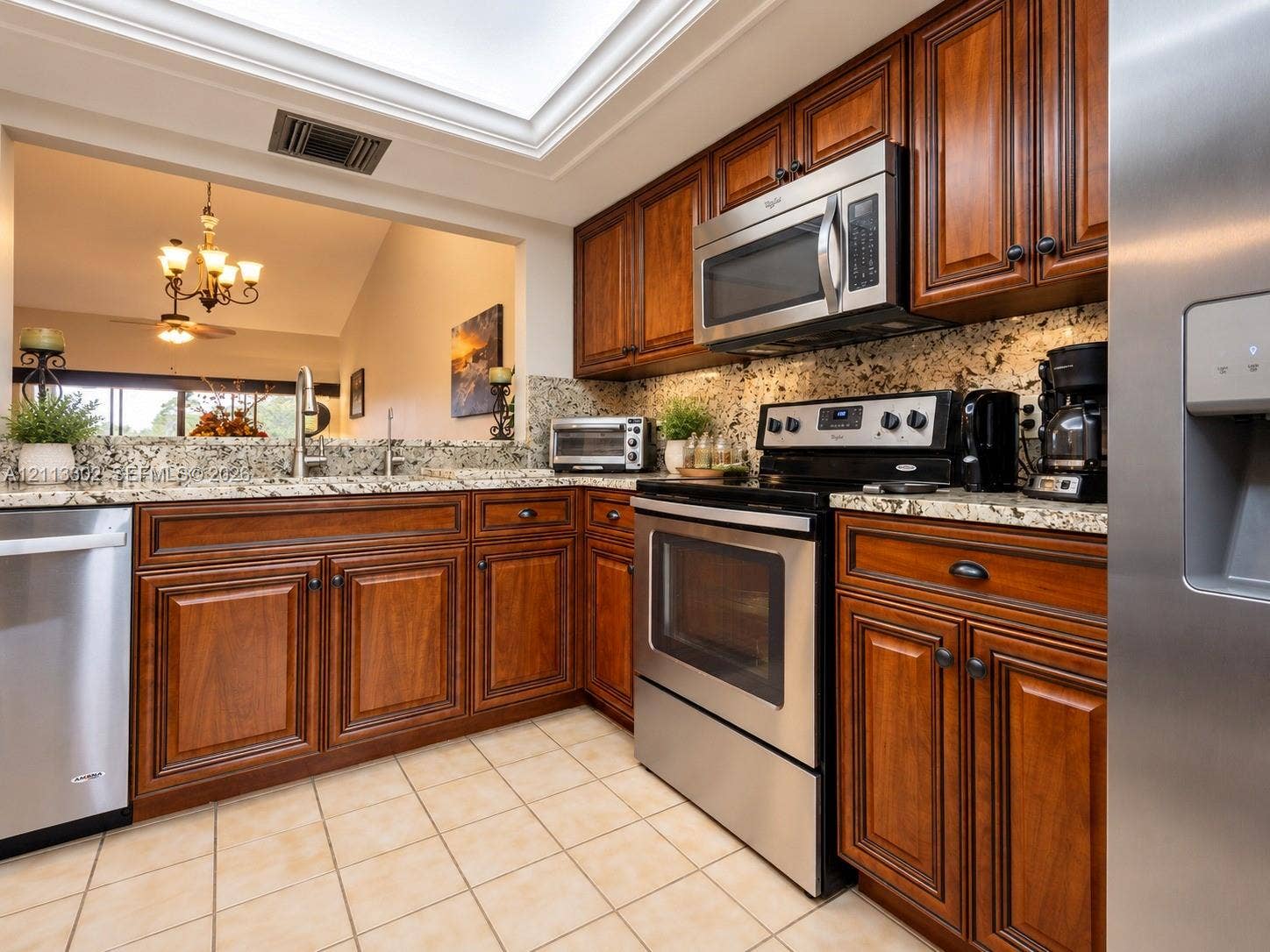 9450 Meadowood Drive, #202, Fort Pierce, FL 34951 Kitchen featuring stained wood cabinetry, stone countertops, stainless steel appliances, and a recessed ceiling skylight