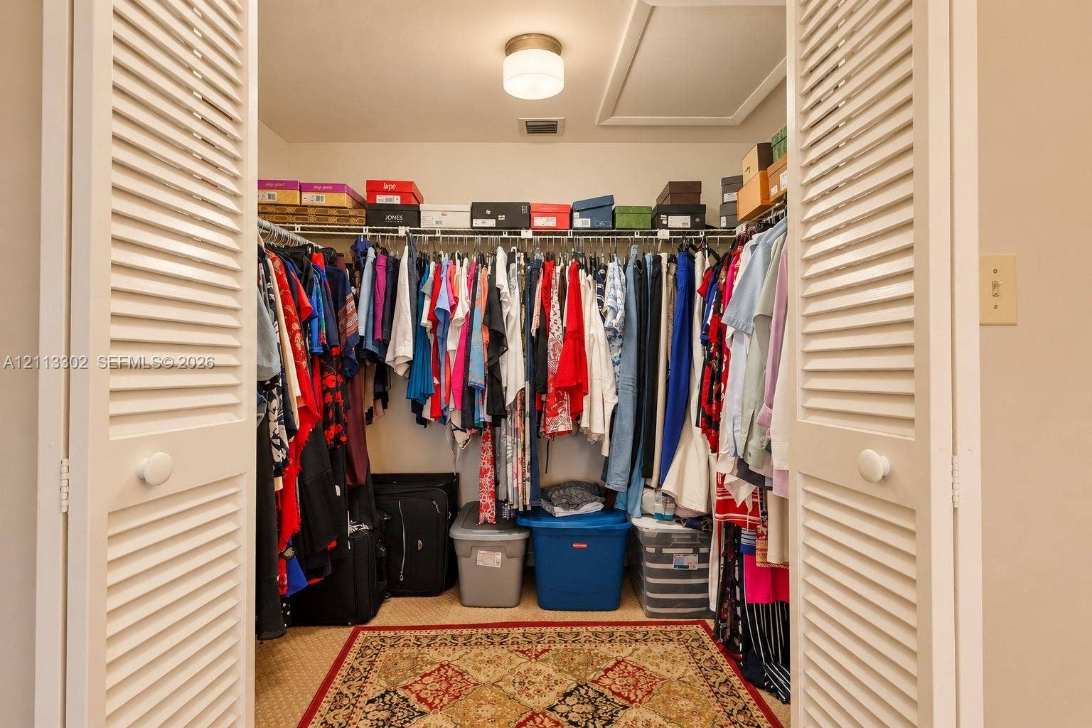 9450 Meadowood Drive, #202, Fort Pierce, FL 34951 Storage closet featuring white louvered doors, wire shelving, and a central flush-mount ceiling light fixture