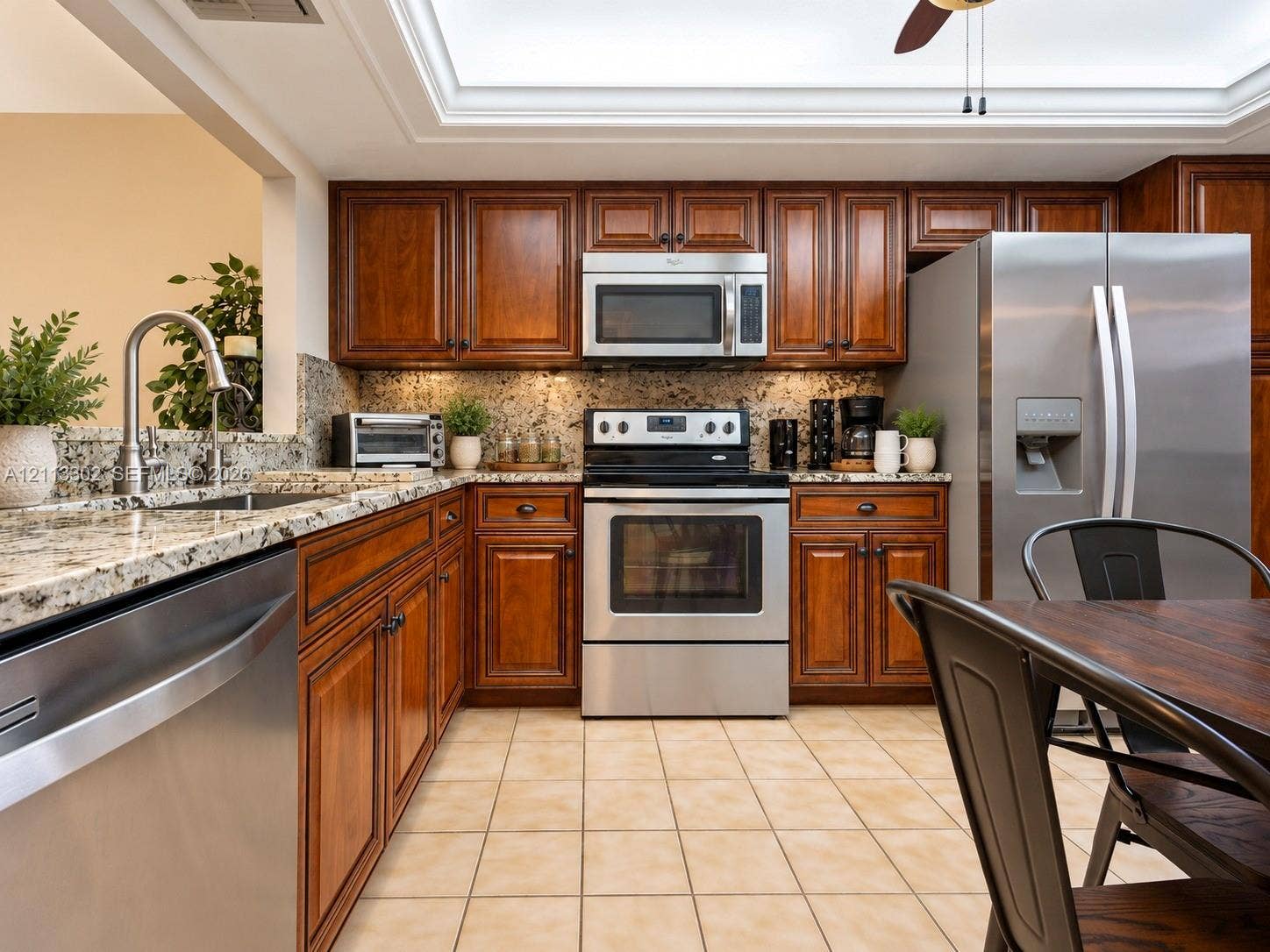 9450 Meadowood Drive, #202, Fort Pierce, FL 34951 Kitchen featuring stained wood cabinetry, stone countertops, stainless steel appliances, a skylight, and tile flooring