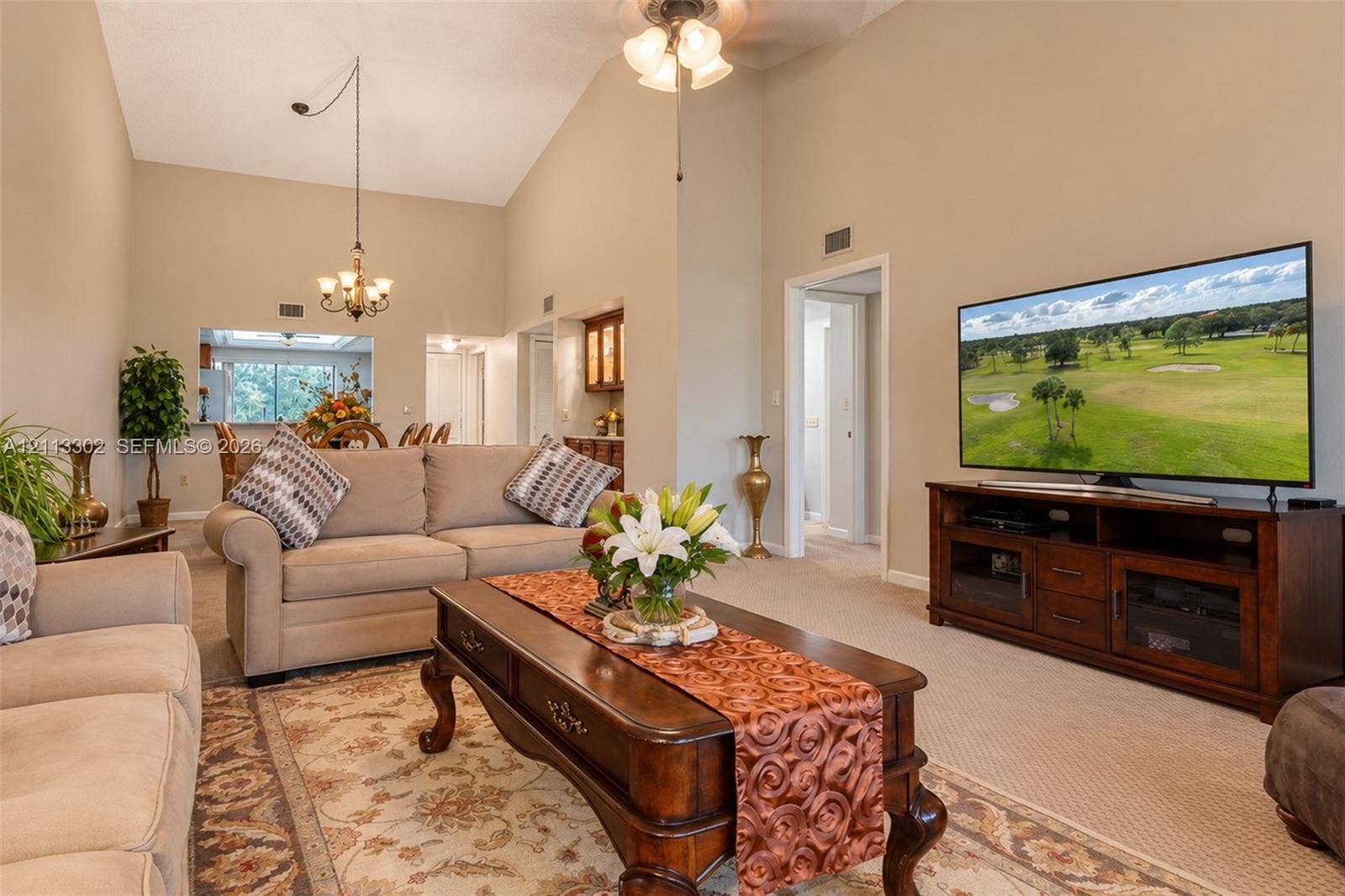 9450 Meadowood Drive, #202, Fort Pierce, FL 34951 Vaulted ceilings, formal chandelier, and built-in cabinetry featuring glass-front display shelving