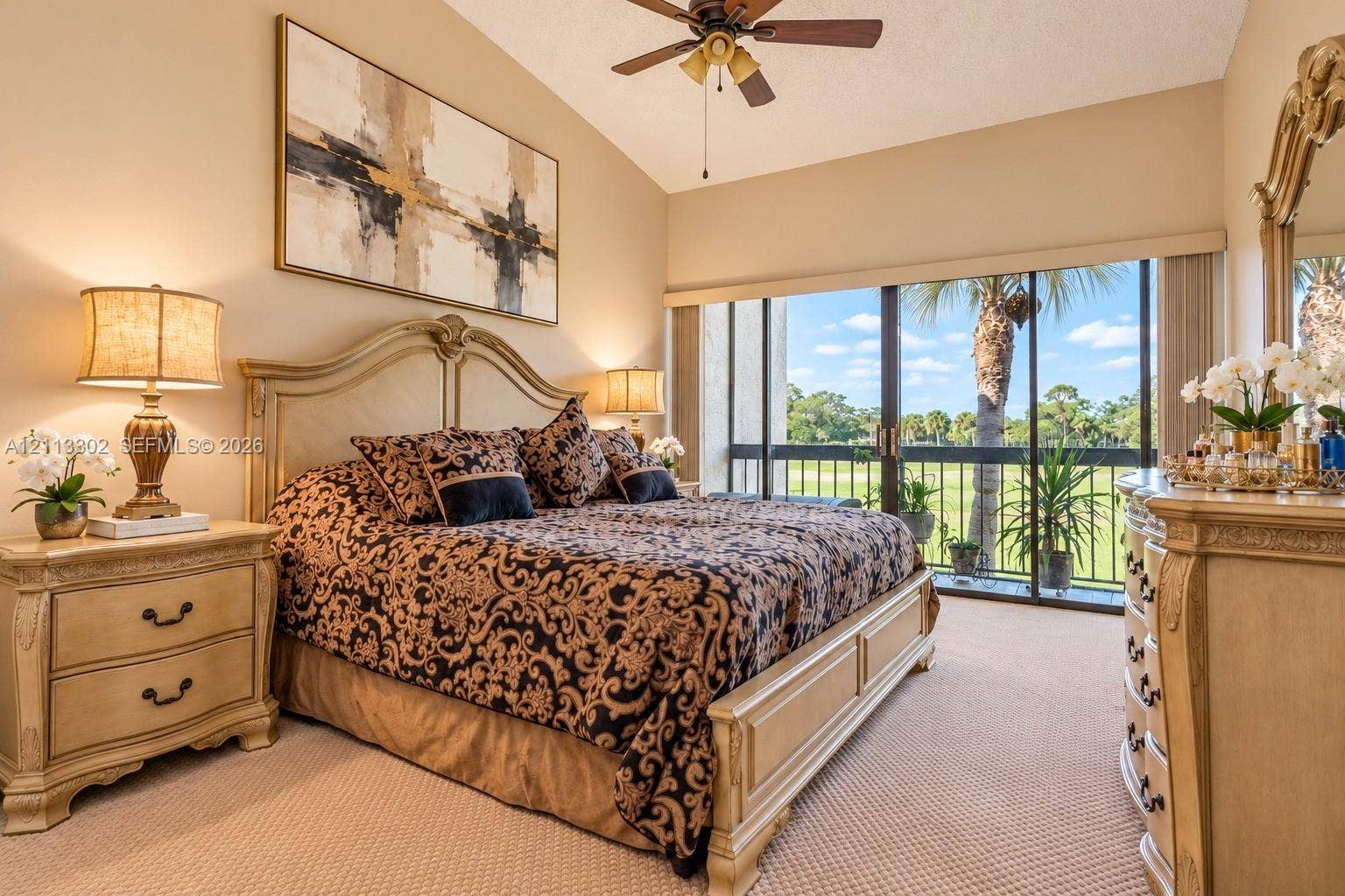 9450 Meadowood Drive, #202, Fort Pierce, FL 34951 Vaulted ceiling, ceiling fan, and floor-to-ceiling sliding glass doors opening to a balcony with exterior greenery