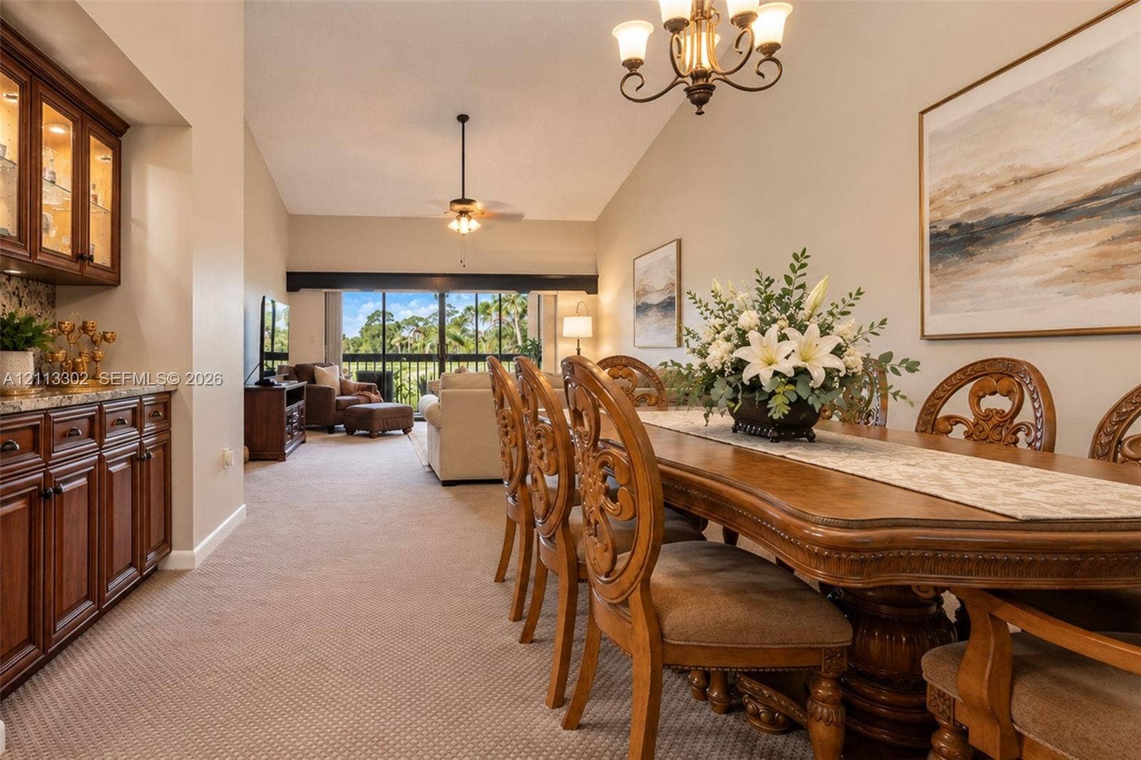 9450 Meadowood Drive, #202, Fort Pierce, FL 34951 Dining area featuring vaulted ceilings, built-in wooden cabinetry with countertop space, a decorative chandelier, and a floor-to-ceiling sliding glass door