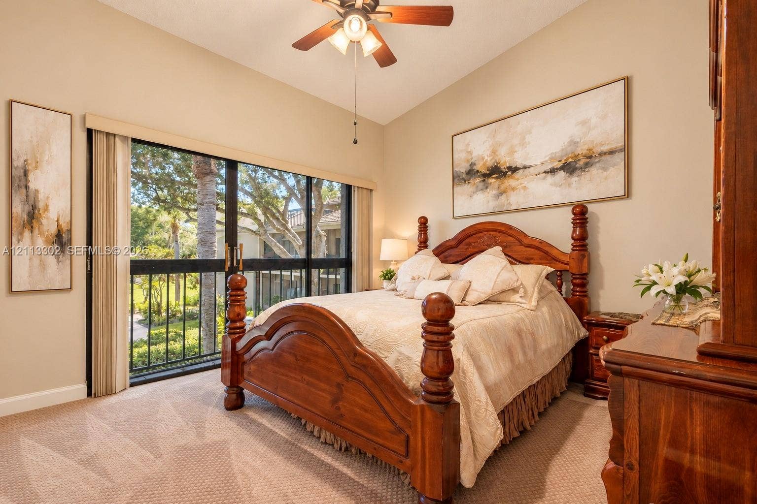 9450 Meadowood Drive, #202, Fort Pierce, FL 34951 Vaulted ceiling featuring a central ceiling fan with integrated lighting, wall-to-wall carpeting, and sliding glass doors with black framing
