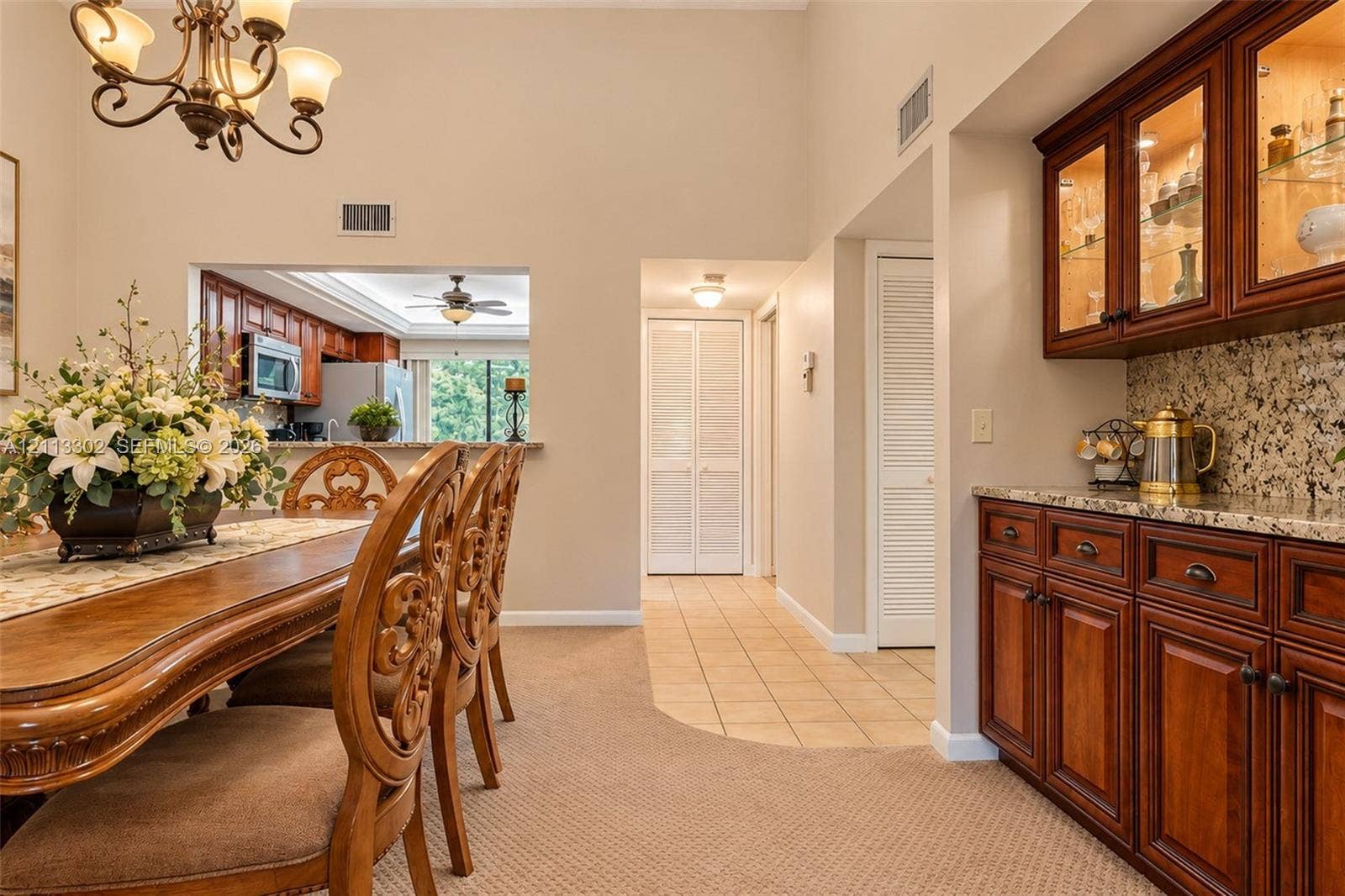 9450 Meadowood Drive, #202, Fort Pierce, FL 34951 Dining area featuring high vaulted ceilings, wrought-iron chandelier, and built-in cabinetry with glass-front uppers and stone countertops